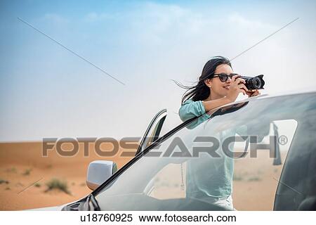 Female tourist photographing from off road vehicle in desert, Dubai, United Arab Emirates View Large Photo Image Stock Photography - Female tourist photographing from off road vehicle in desert, Dubai, United Arab Emirates. Fotosearch