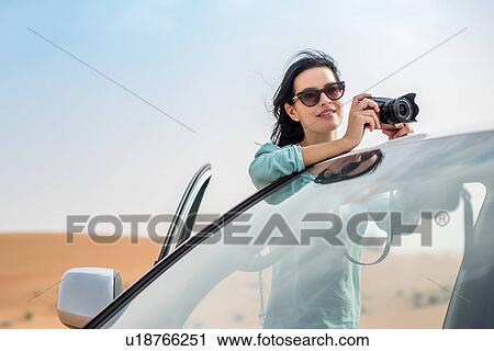 Female tourist photographing over off road vehicle in desert, Dubai, United Arab Emirates View Large Photo Image Stock Image - Female tourist photographing over off road vehicle in desert, Dubai, United Arab Emirates. Fotosearch