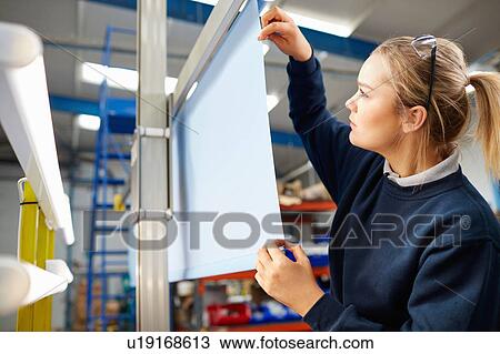 Stock Image - Female worker inspecting fabric in roller blind factory. Fotosearch