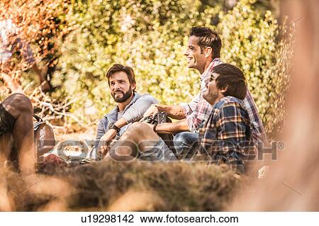 Stock Image - Four male hikers taking a break in forest, Deer Park, Cape Town, South Africa. Fotosearch