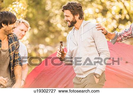 Stock Photo - Four men drinking beer whilst camping in forest, Deer Park, Cape Town, South Africa. Fotosearch