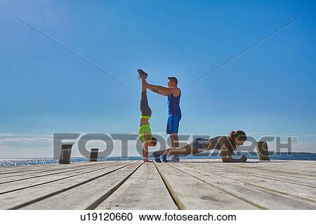 Stock Image - Friends on pier doing handstands and push ups. Fotosearch
