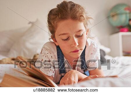 Girl lying on bed reading book View Large Photo Image Stock Image - Girl lying on bed reading book. Fotosearch