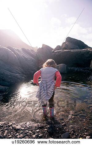 Stock Photograph - Girl playing in pool of water, Millook Beach, Cornwall. Fotosearch