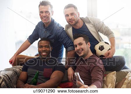 Stock Image - Group of male friends with italian flag face paint holding football and beer bottles looking at camera smiling. Fotosearch