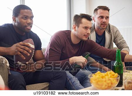 Group of men holding ball watching sports event on television with snacks and beers View Large Photo Image Stock Image - Group of men holding ball watching sports event on television with snacks and beers. Fotosearch