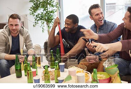 Group of men in lounge sitting around table with beer bottles and snacks talking, smiling View Large Photo Image Stock Photo - Group of men in lounge sitting around table with beer bottles and snacks talking, smiling. Fotosearch