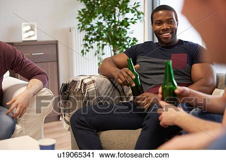 Group of men sitting in lounge holding beer bottles smiling View Large Photo Image Stock Image - Group of men sitting in lounge holding beer bottles smiling. Fotosearch