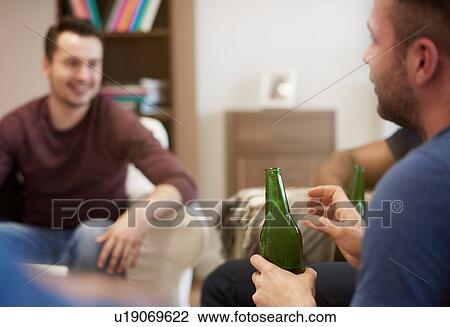 Group of men sitting in lounge holding beer bottles chatting View Large Photo Image Stock Image - Group of men sitting in lounge holding beer bottles chatting. Fotosearch