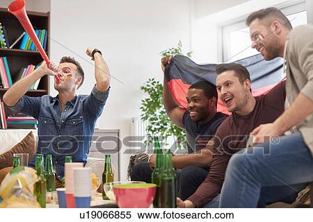 Stock Photography - Group of men watching sporting event on television holding German flag celebrating. Fotosearch