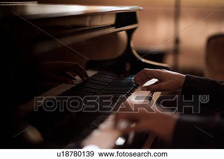 Hands of young man playing piano keys in bar at night View Large Photo Image Stock Photo - Hands of young man playing piano keys in bar at night. Fotosearch