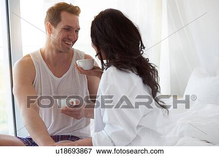 Happy young couple having coffee on bed View Large Photo Image Stock Photo - Happy young couple having coffee on bed. Fotosearch