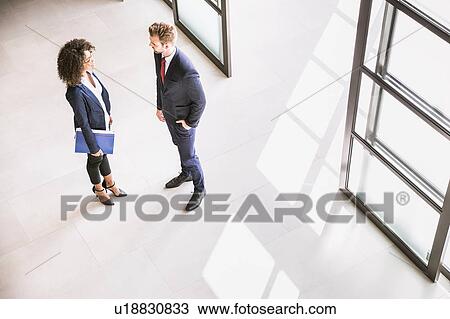 High angle view of businessman and woman talking at office entrance View Large Photo Image Stock Image - High angle view of businessman and woman talking at office entrance. Fotosearch
