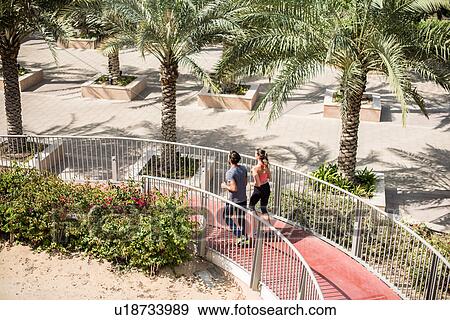 High angle view of running couple running down footbridge, Dubai, United Arab Emirates View Large Photo Image Stock Photo - High angle view of running couple running down footbridge, Dubai, United Arab Emirates. Fotosearch