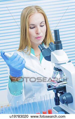 Stock Image - Lab assistant using a microscope. Fotosearch