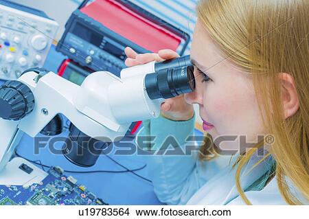 Picture - Lab assistant using microscope. Fotosearch