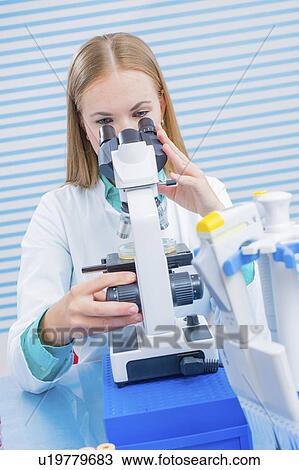 Stock Image - Lab assistant using microscope. Fotosearch