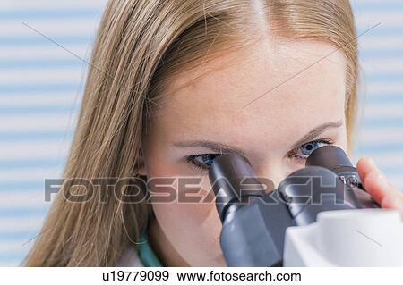 Stock Photo - Lab assistant using microscope. Fotosearch