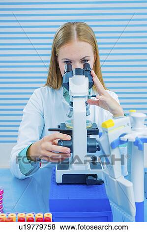 Stock Photo - Lab assistant using microscope. Fotosearch