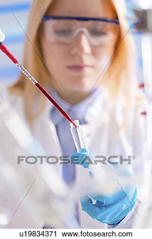 Stock Image - Lab technician dripping chemical. Fotosearch