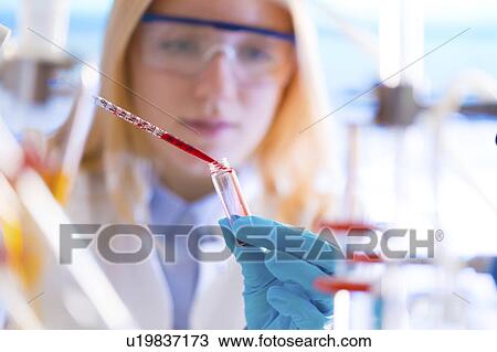 Stock Image - Lab technician dripping chemical. Fotosearch
