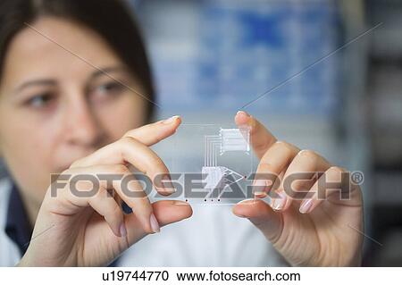 Stock Image - Lab technician holding a lab on a chip. Fotosearch