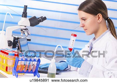 Stock Image - Lab technician holding test tube in lab. Fotosearch