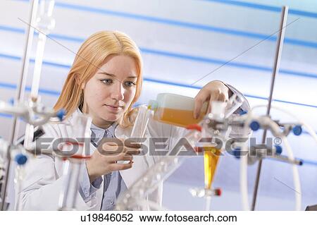 Stock Image - Lab technician pouring chemical. Fotosearch
