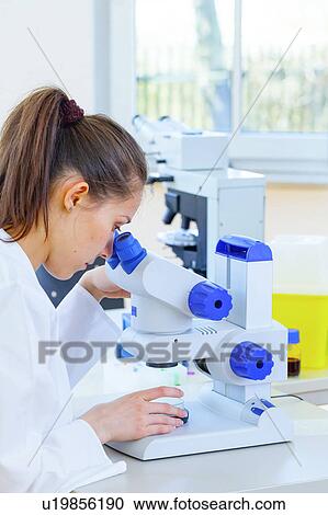 Stock Image - Lab technician using microscope. Fotosearch