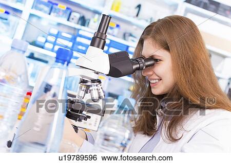 Stock Photograph - Lab technician using microscope. Fotosearch
