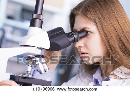 Stock Photograph - Lab technician using microscope. Fotosearch