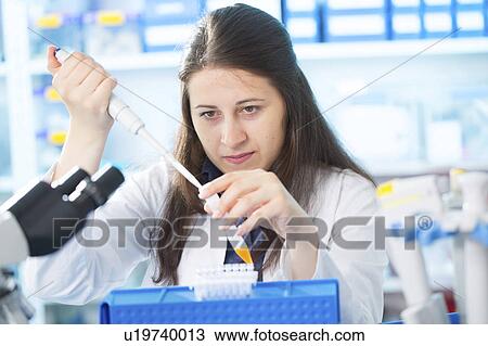 Stock Image - Lab technician using pipette in lab. Fotosearch