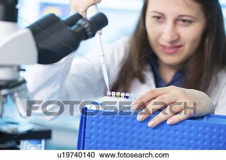 Stock Image - Lab technician using pipette in lab. Fotosearch