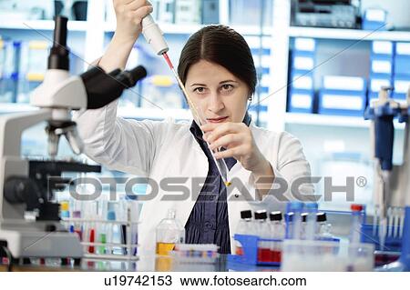 Stock Image - Lab technician using pipette. Fotosearch
