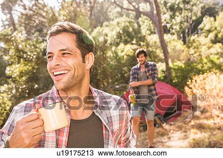 Stock Image - Male camper with coffee in forest, Deer Park, Cape Town, South Africa. Fotosearch