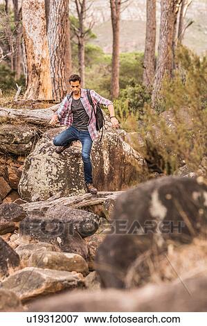 Stock Photo - Male hiker hiking down forest rock formation, Deer Park, Cape Town, South Africa. Fotosearch
