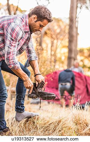 Stock Photo - Male hiker putting on hiking boot in forest, Deer Park, Cape Town, South Africa. Fotosearch