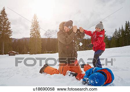 Stock Photo - Man and sons having snowball fight in winter, Elmau, Bavaria, Germany. Fotosearch