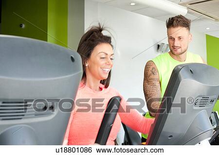 Man and woman in gym using exercise machine smiling View Large Photo Image Stock Photograph - Man and woman in gym using exercise machine smiling. Fotosearch
