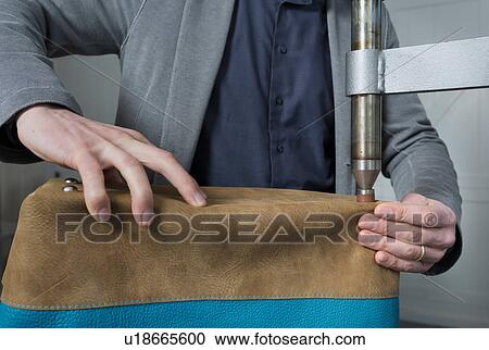 Stock Image - Man applying bag feet to leather holdall. Fotosearch