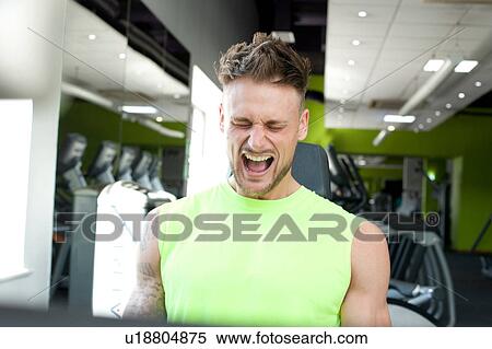 Stock Photography - Man at gym exercising, straining, pulling face. Fotosearch