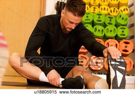 Man at gym sitting doing leg stretching exercises View Large Photo Image Stock Photography - Man at gym sitting doing leg stretching exercises. Fotosearch