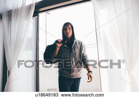 Stock Image - Man in doorway wearing hooded top carrying holdall on shoulder. Fotosearch