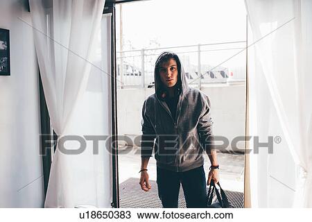 Man in doorway wearing hooded top carrying holdall View Large Photo Image Stock Image - Man in doorway wearing hooded top carrying holdall. Fotosearch