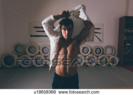 Man in gym putting on shirt looking at camera View Large Photo Image Stock Photo - Man in gym putting on shirt looking at camera. Fotosearch