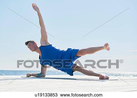 Man on pier resting on elbow, arm raised doing side push up View Large Photo Image Stock Image - Man on pier resting on elbow, arm raised doing side push up. Fotosearch