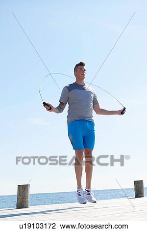 Stock Image - Man on pier using skipping rope. Fotosearch