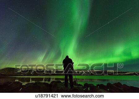 Stock Image - Man photographing Northern Lights, Kleifarvatn, Iceland. Fotosearch