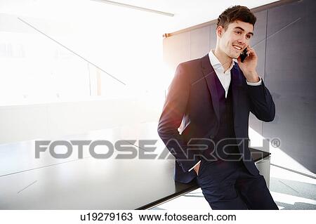 Man sitting on desk making telephone call smiling View Large Photo Image Stock Image - Man sitting on desk making telephone call smiling. Fotosearch