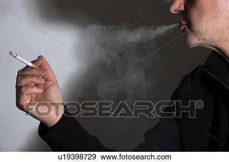 Man smoking a cigarette exhaling smoke View Large Photo Image Stock Photo - Man smoking a cigarette exhaling smoke. Fotosearch